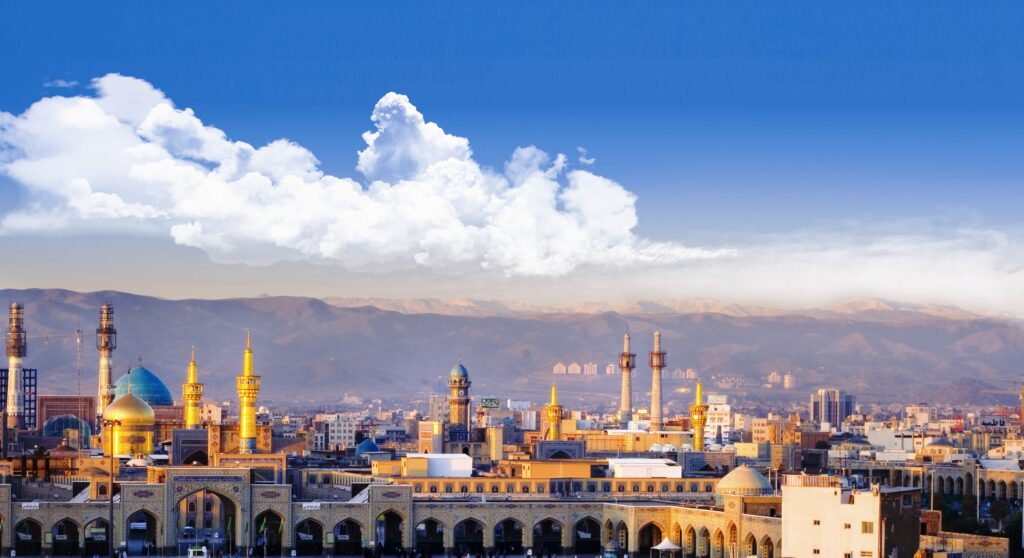 عکس هوایی حرم امام رضا (ع) و مسجد گوهرشاد با پس‌زمینه شهر مشهد و کوه‌های بینالود