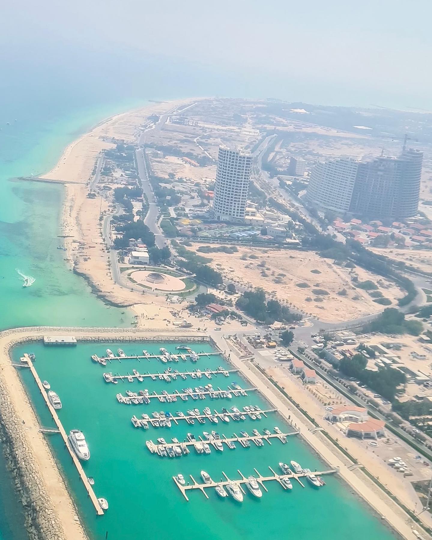 نمای هوایی ساحل جزیره کیش با مارینا و برج‌های مرتفع کنار آب‌های فیروزه‌ای